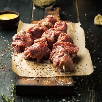 Raw meat on skewers. BBQ meat with spices on a wooden background